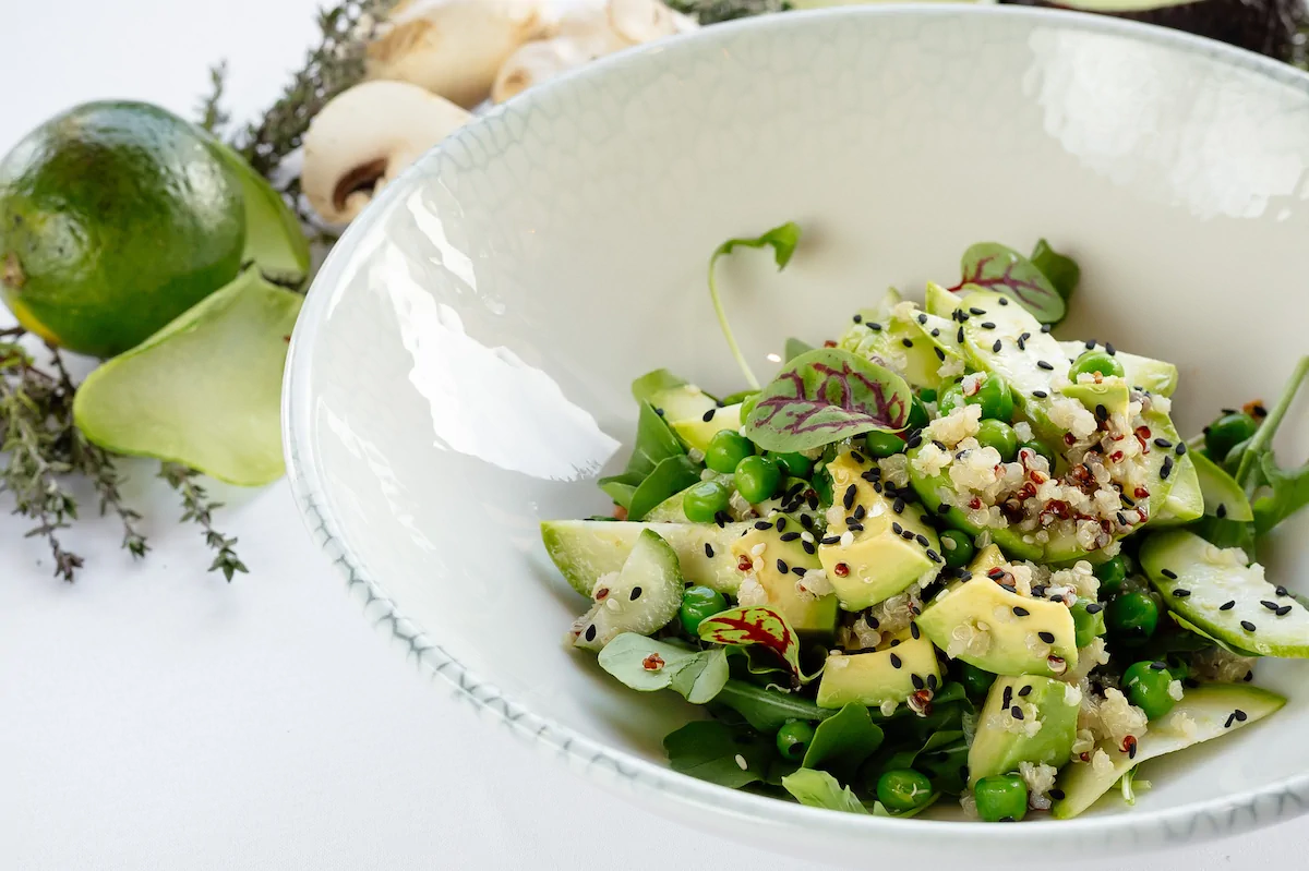 Зеленый салат с авокадо, киноа и соусом из вяленых томатов.